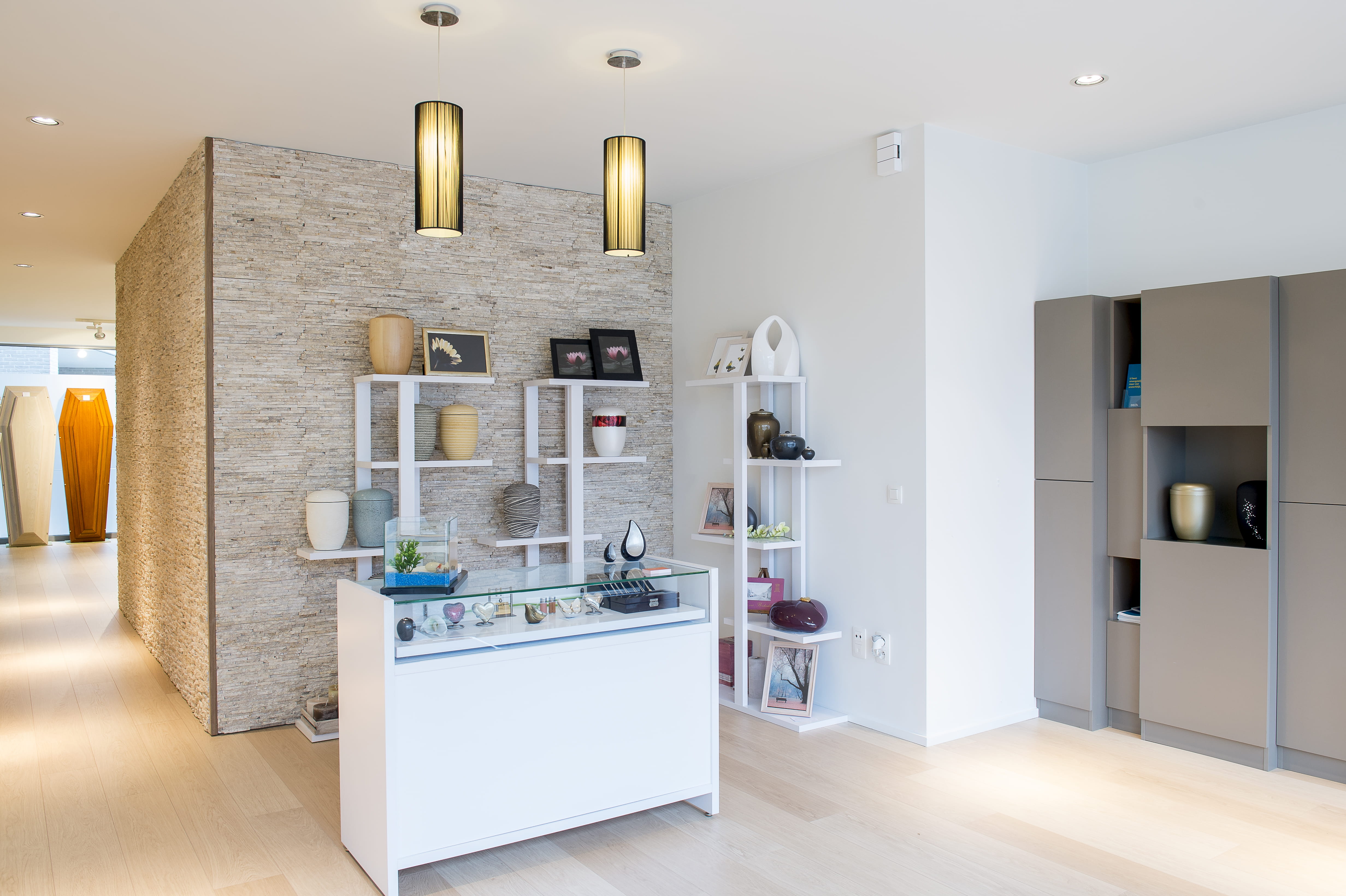 Ontvangstruimte met witte dressoirkast en rouwboeketten